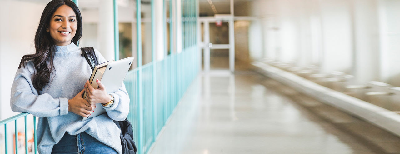 Girl holding laptop and books